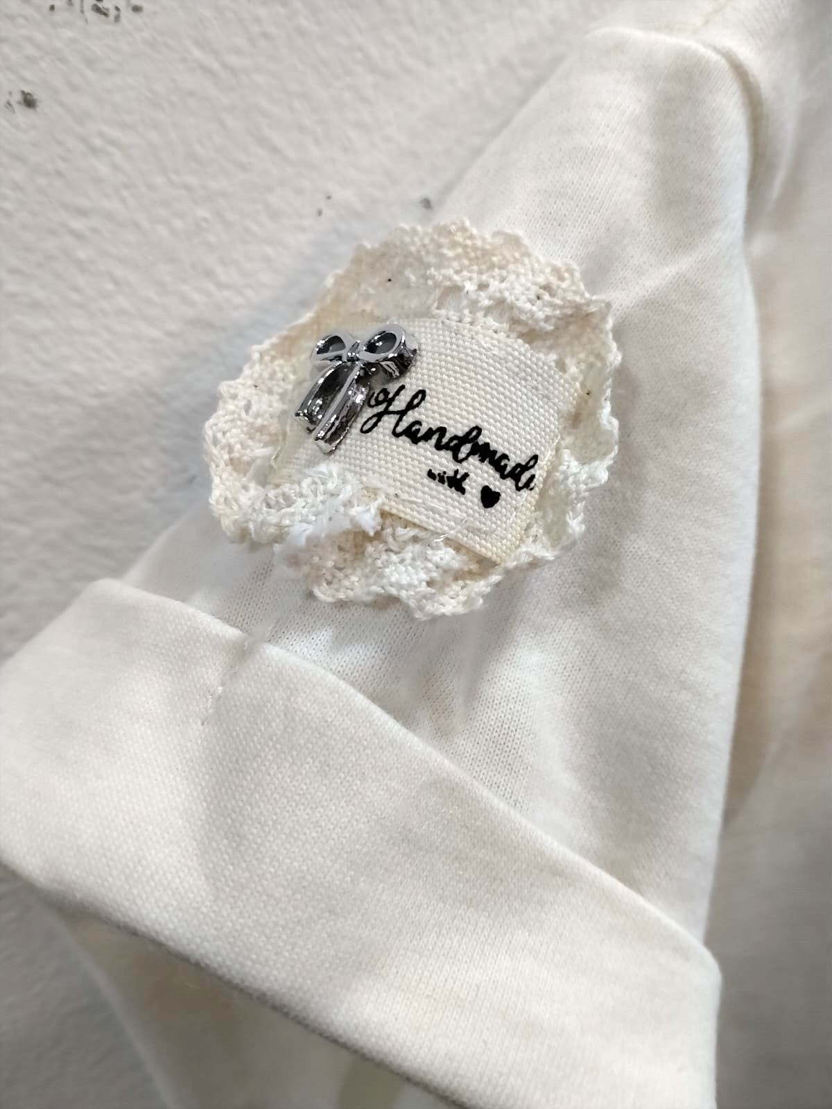 Camiseta marfil con detalles de piedras y aplique en manga 3100
